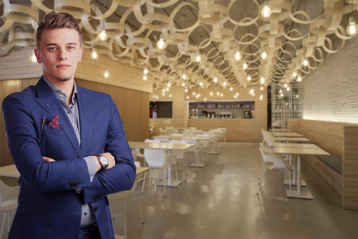 Young restaurant owner standing proudly in his small business