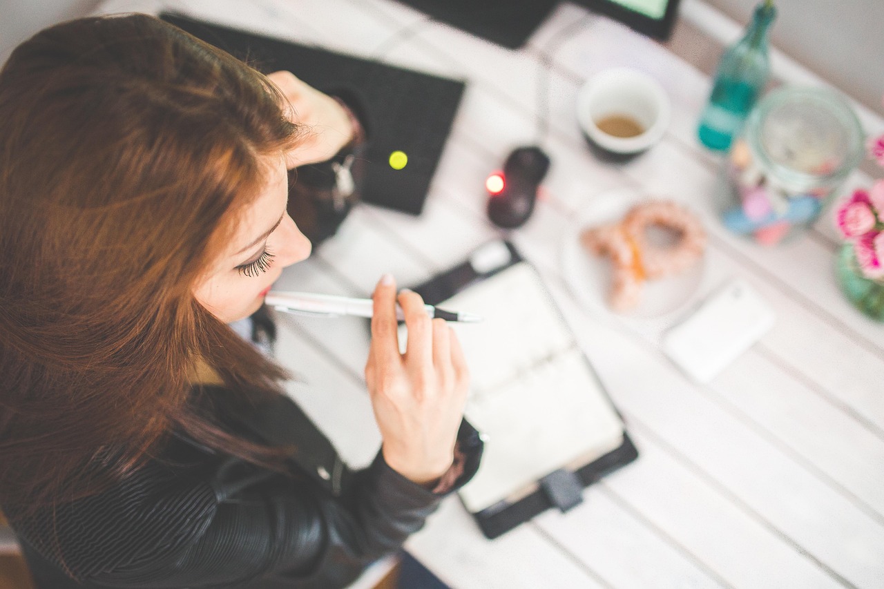 Woman reviewing notes and reflecting at her desk