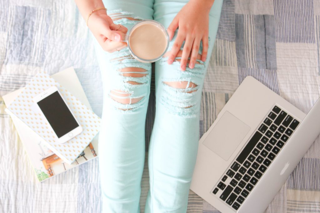 Influencer sitting on floor with coffee and laptop